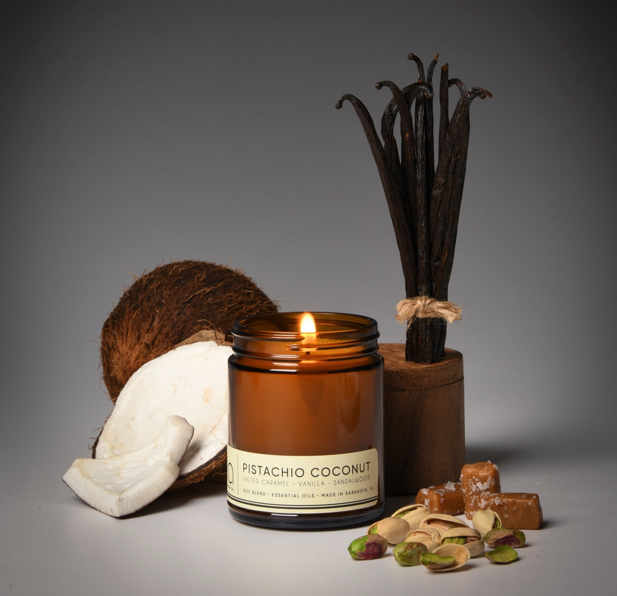 Amber jar candle with lit wick, cream label, and coconut and nut decor