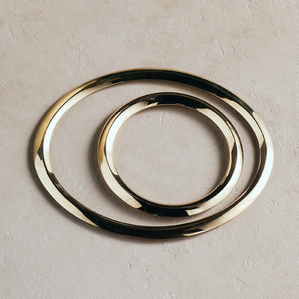 Set of 2 round metal trivets with smooth gold and dark layered ring design.