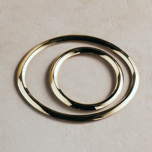 Set of 2 round metal trivets with smooth gold and dark layered ring design.