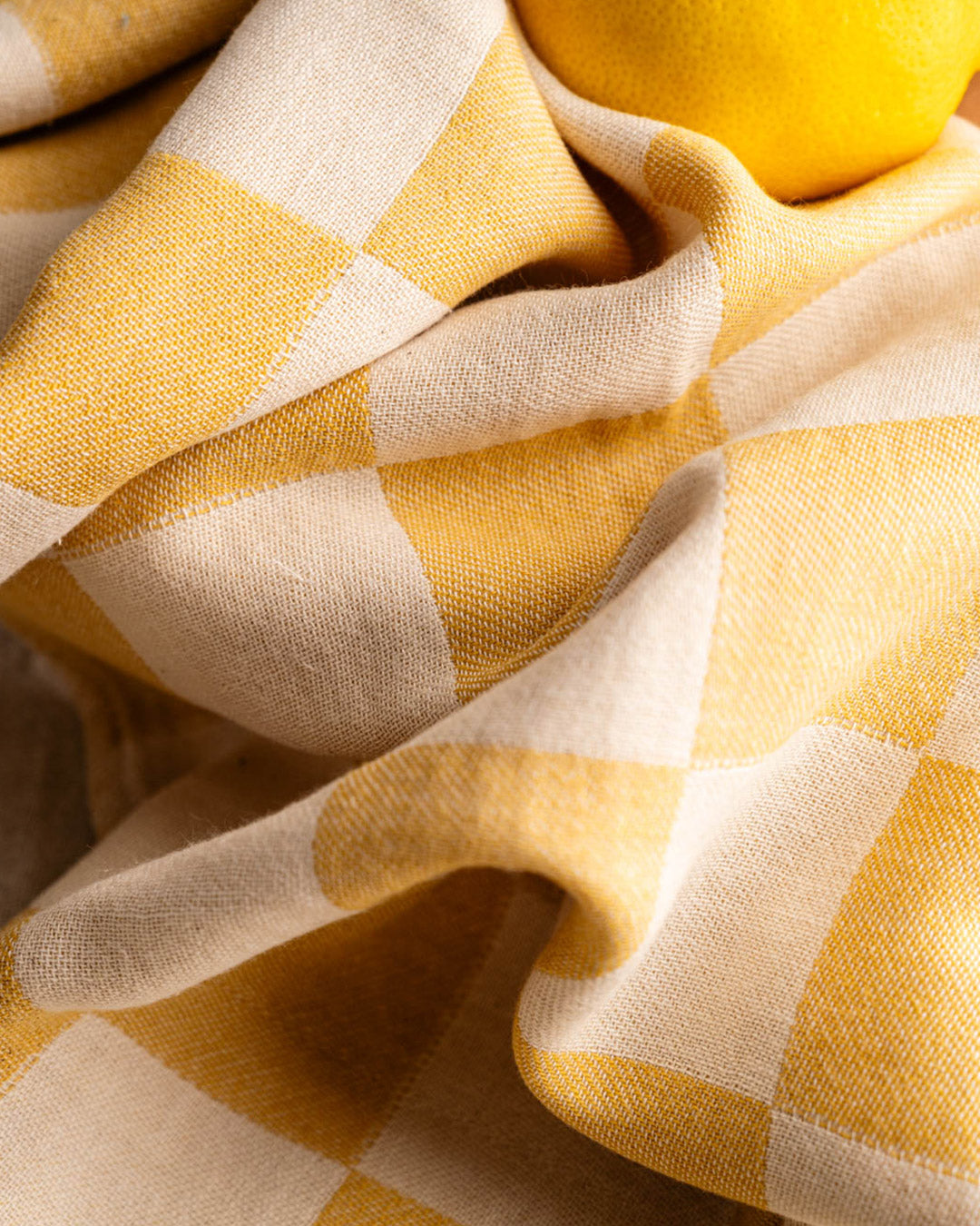 Folded kitchen towel fabric close-up with yellow-and-cream check pattern