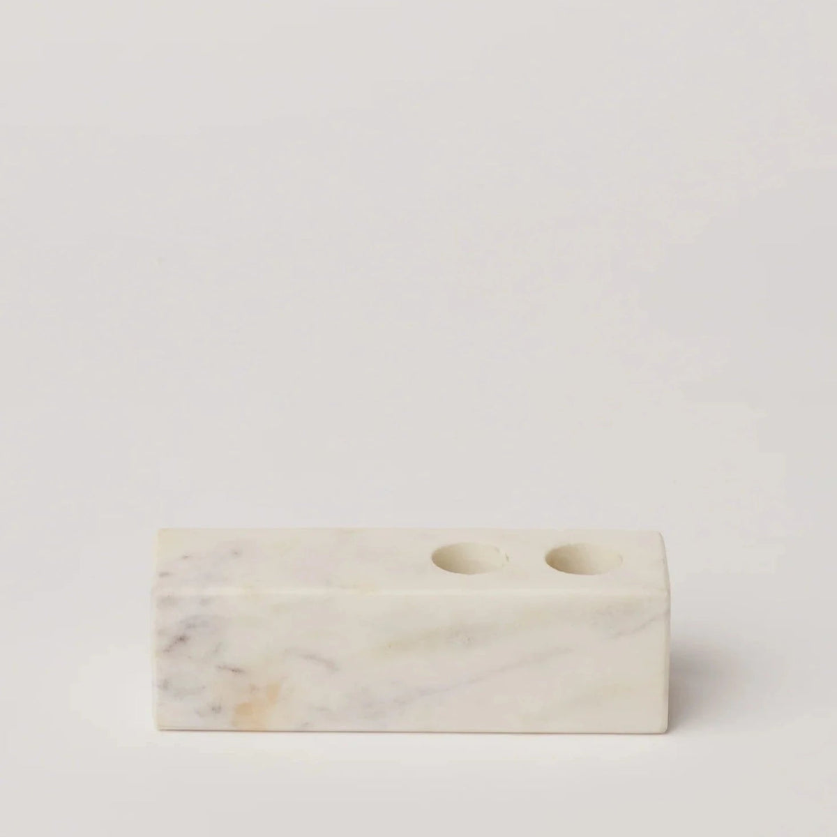 Marble candle holder block with two round openings, white veined stone