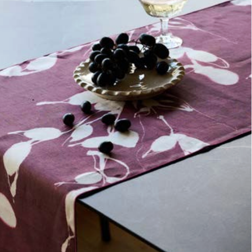 Aubergine table runner with white floral print, draped on a table