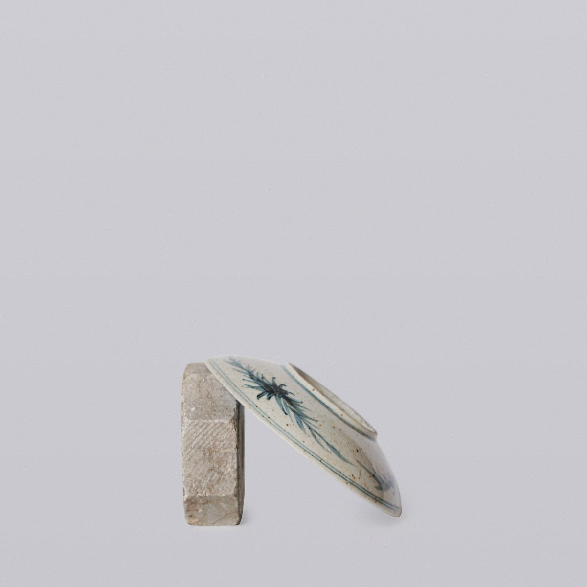 Small porcelain dish side view with blue floral and bamboo-style rim design