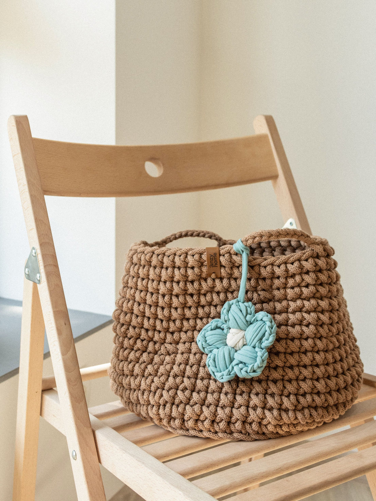Crochet storage basket in brown with teal braided flower and side handle loops