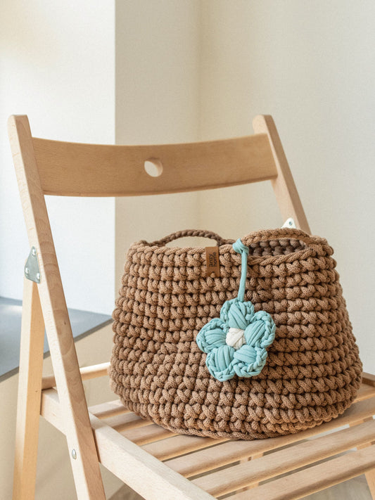 Crochet storage basket in brown with teal braided flower and side handle loops