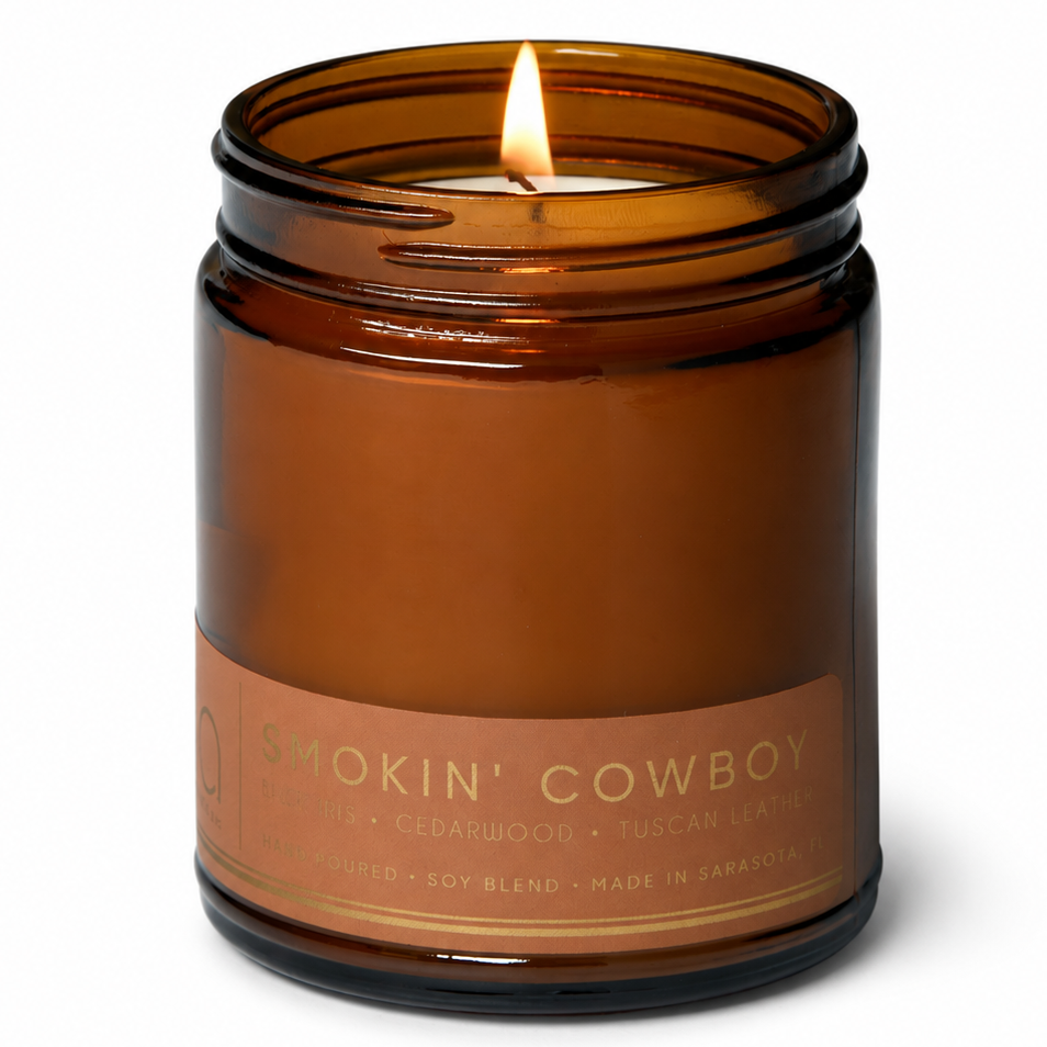 Amber glass candle jar with burning wick and 'Smokin' Cowboy' label