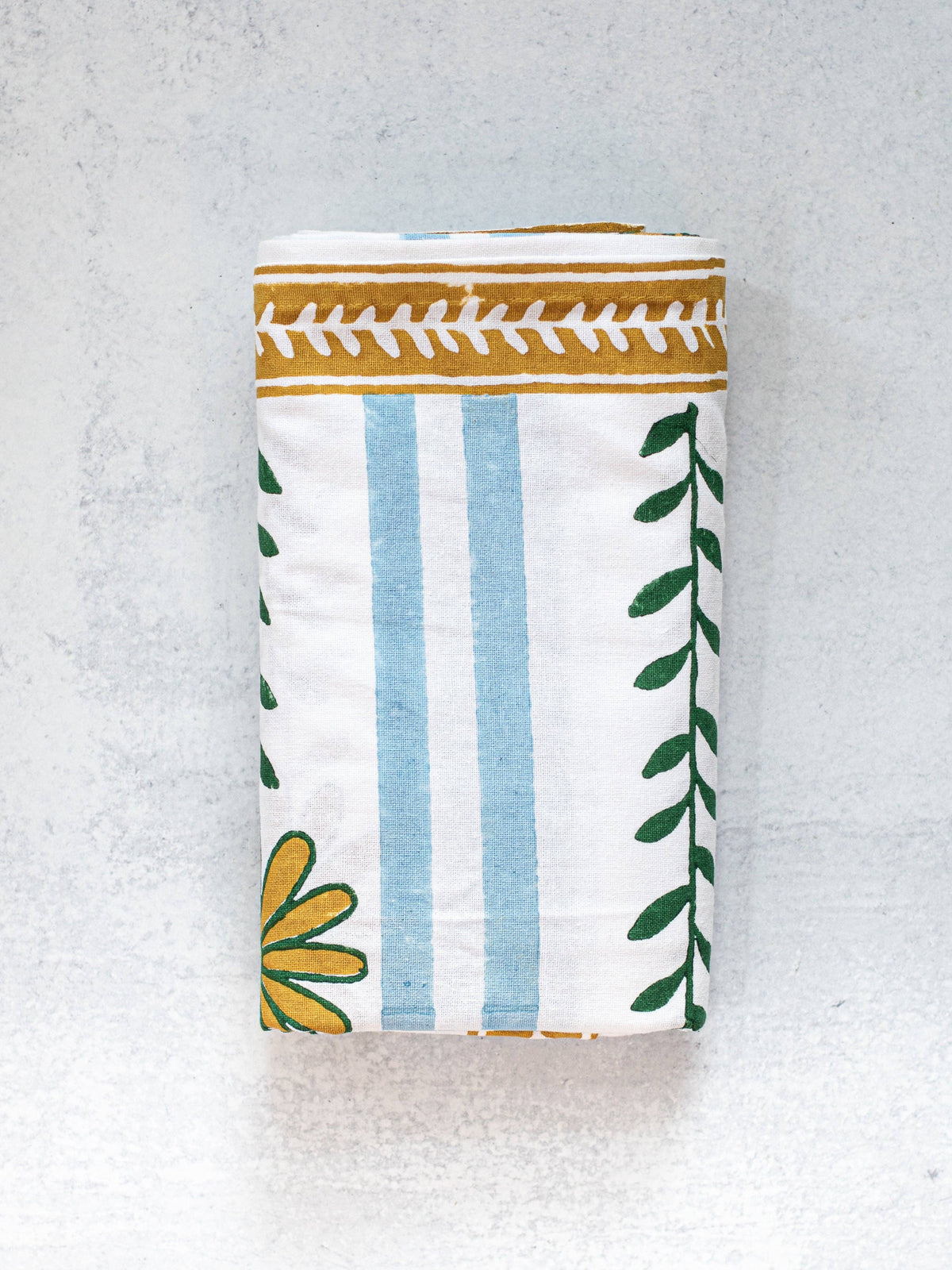 Folded table throw rectangle with blue stripes, green leaves, and mustard trim.
