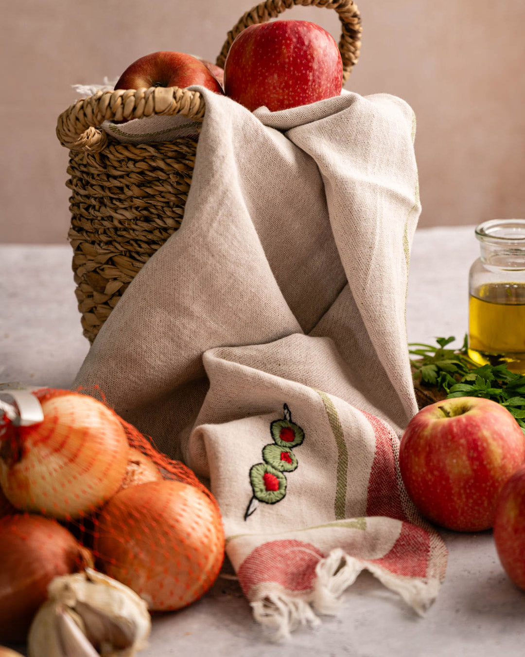 Folded kitchen towel with cream cloth, red stripe trim, and green olive embroidery
