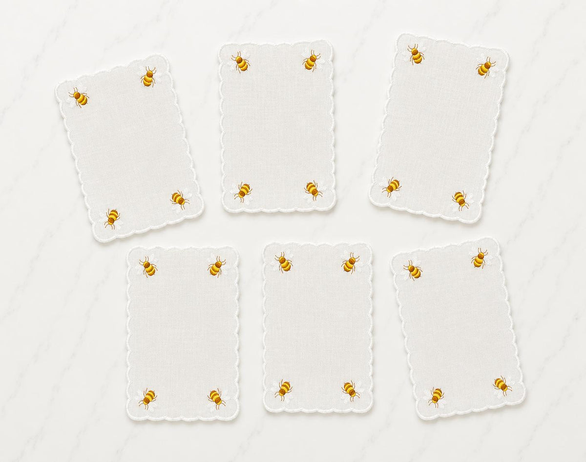 Six white cocktail napkins with scalloped edges, embroidered honey bees in corners