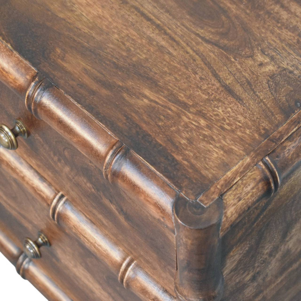 Close-up of brown wood nightstand corner with bamboo-style rounded frame detailing