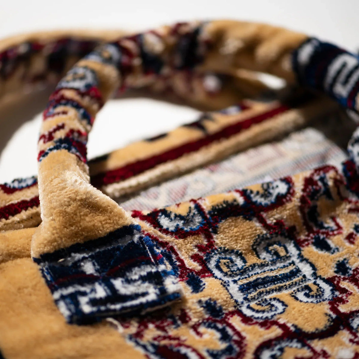 Close-up of embroidered rug-pattern fabric lining and handle strap on the tote bag