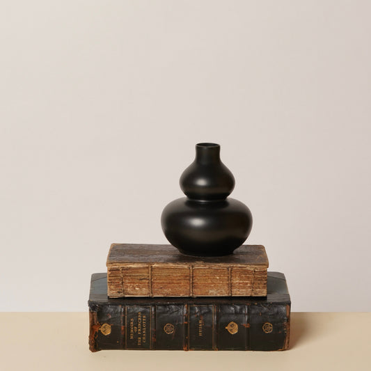 Matte black Heidi vase with rounded bulb body and narrow neck on wood blocks