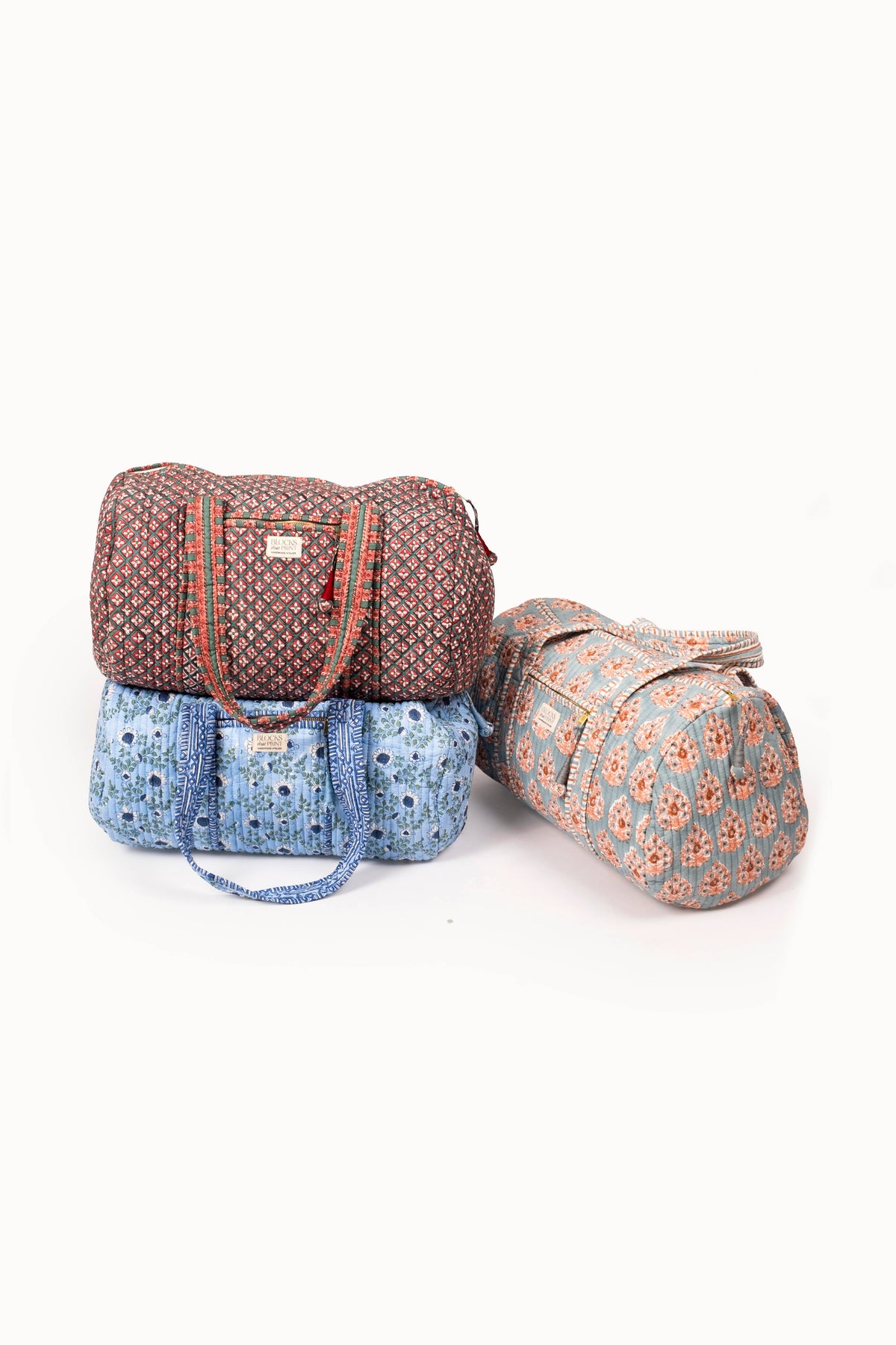 Quilted duffle bags with red-and-green and blue prints, each with zip top and strap