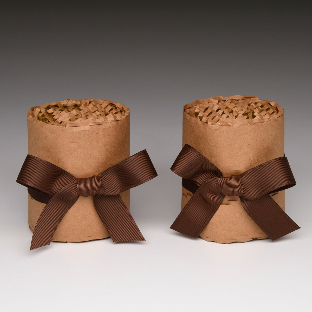 Two kraft paper candle gift boxes with brown ribbon bows
