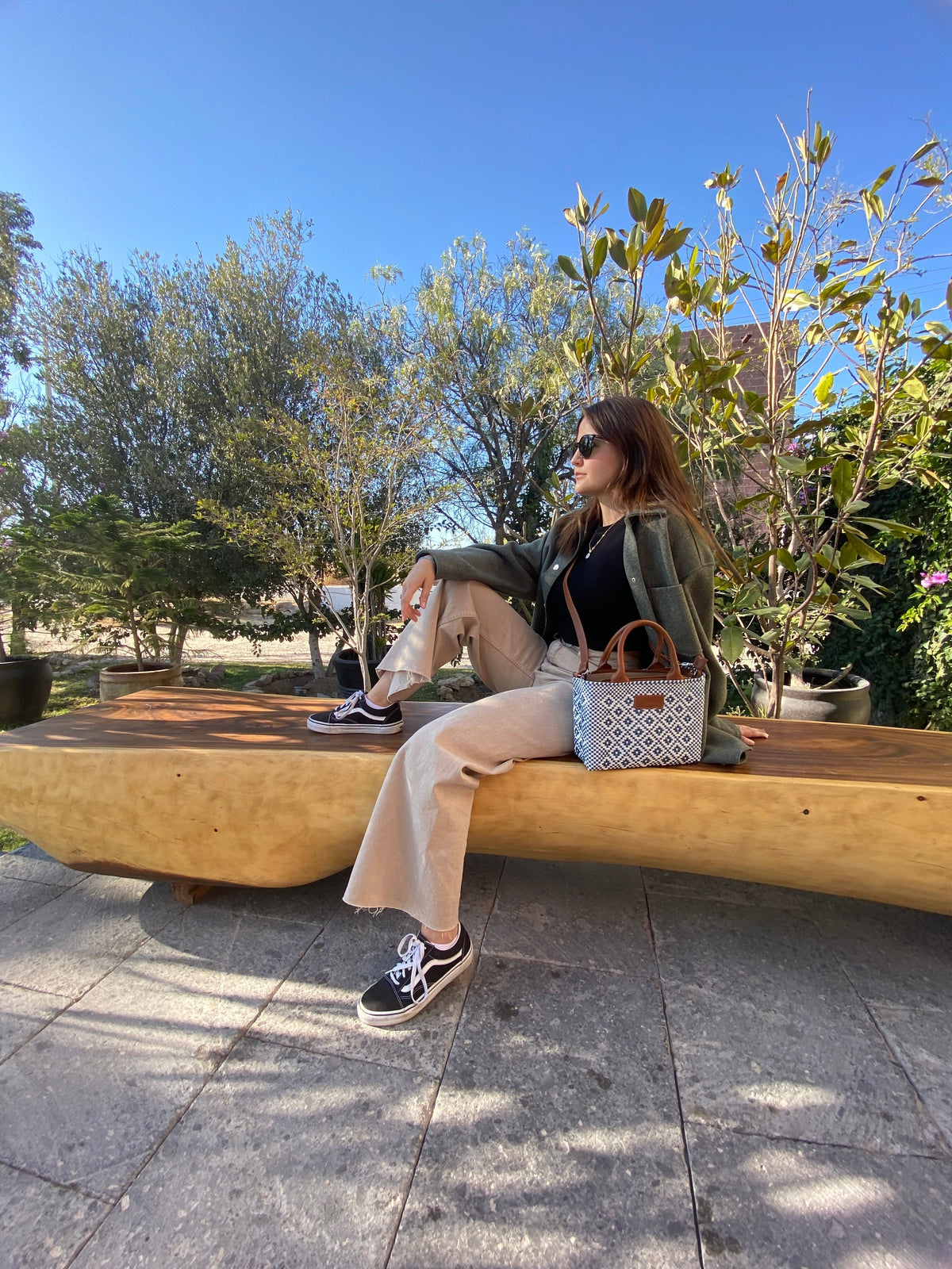 Woven crossbody bag with blue-and-white pattern and tan leather handles, carried by person