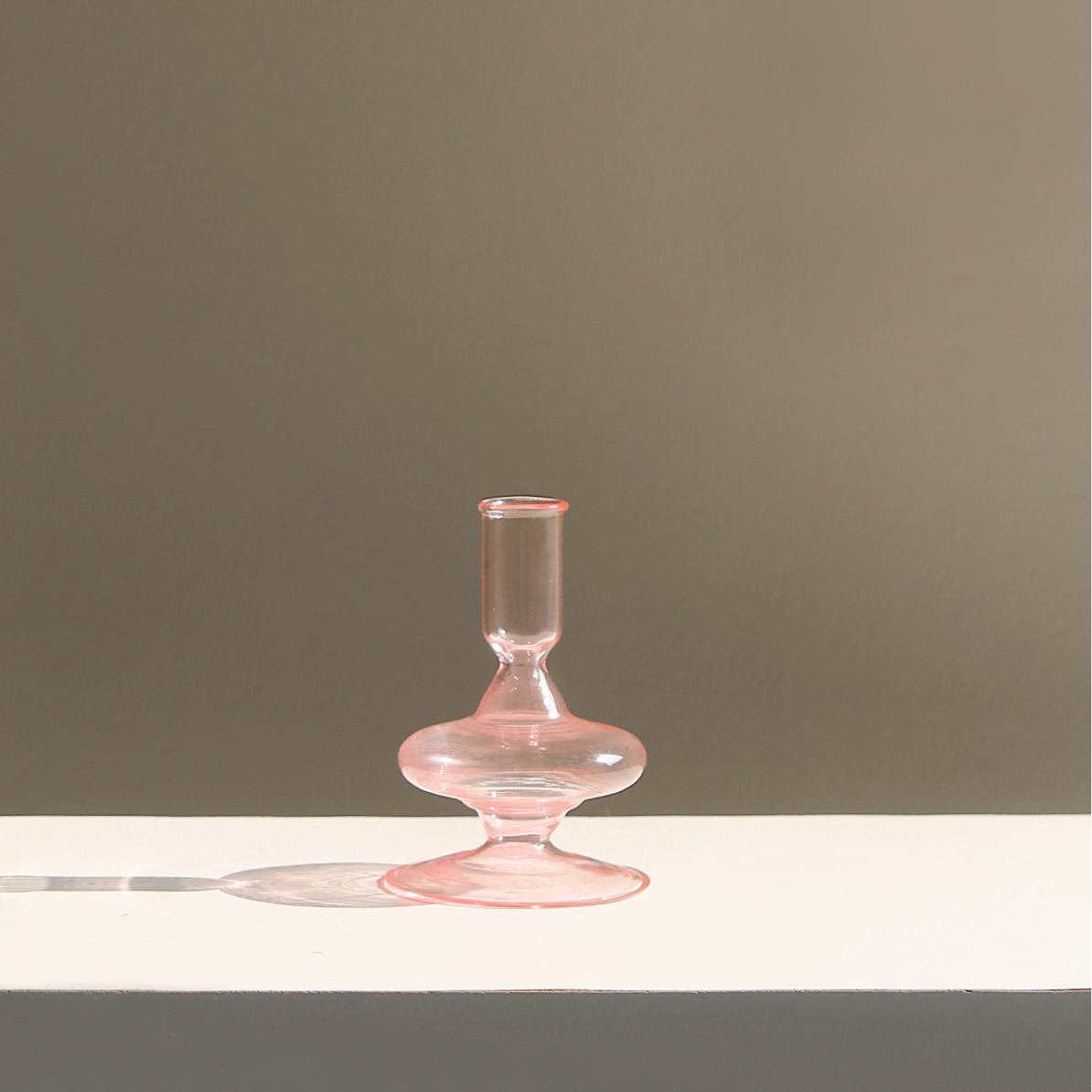 Siri pink glass candle holder with short stem, round base, and cylindrical cup