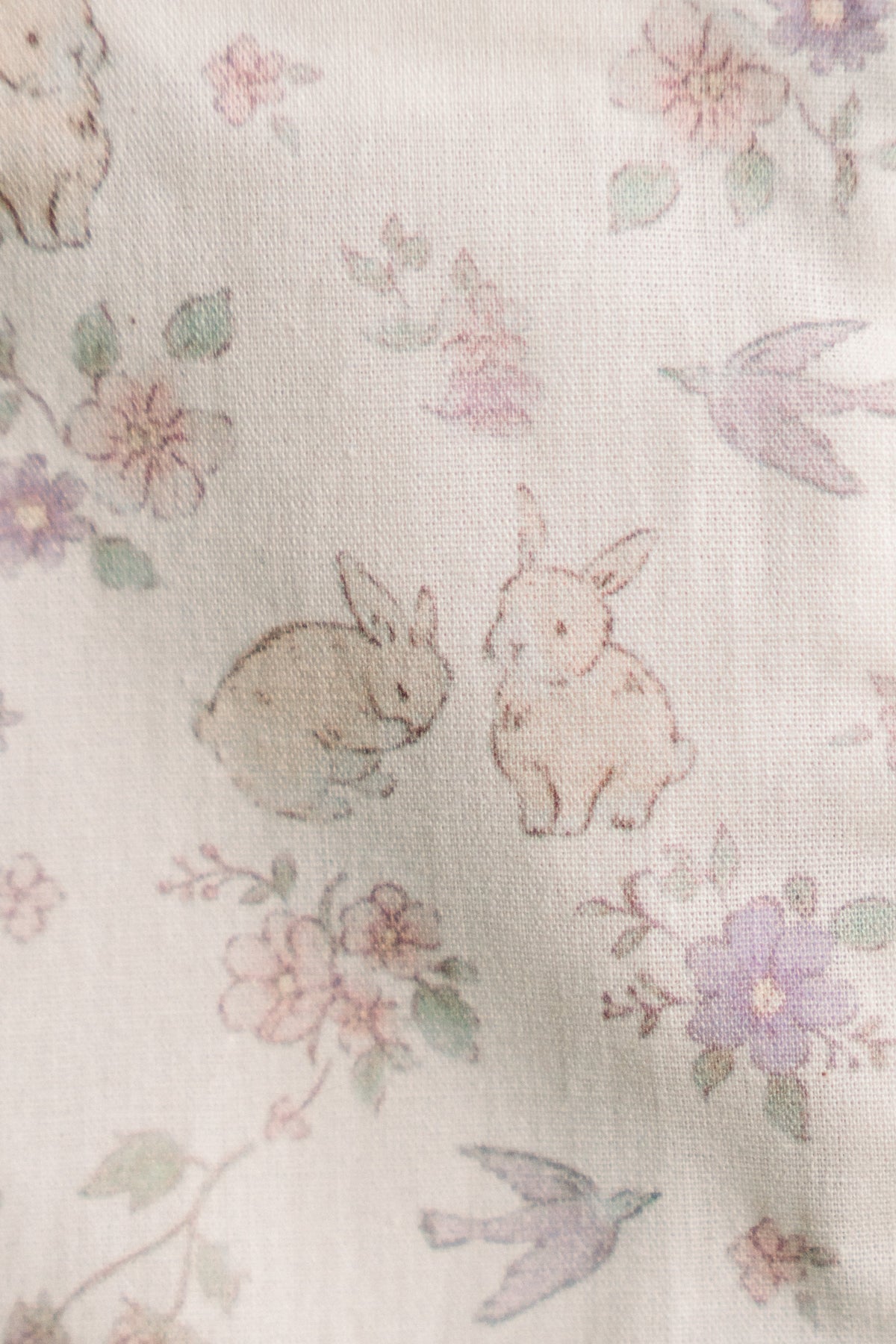 Close-up of woodland floral fabric with rabbits, flowers, and leaves pattern