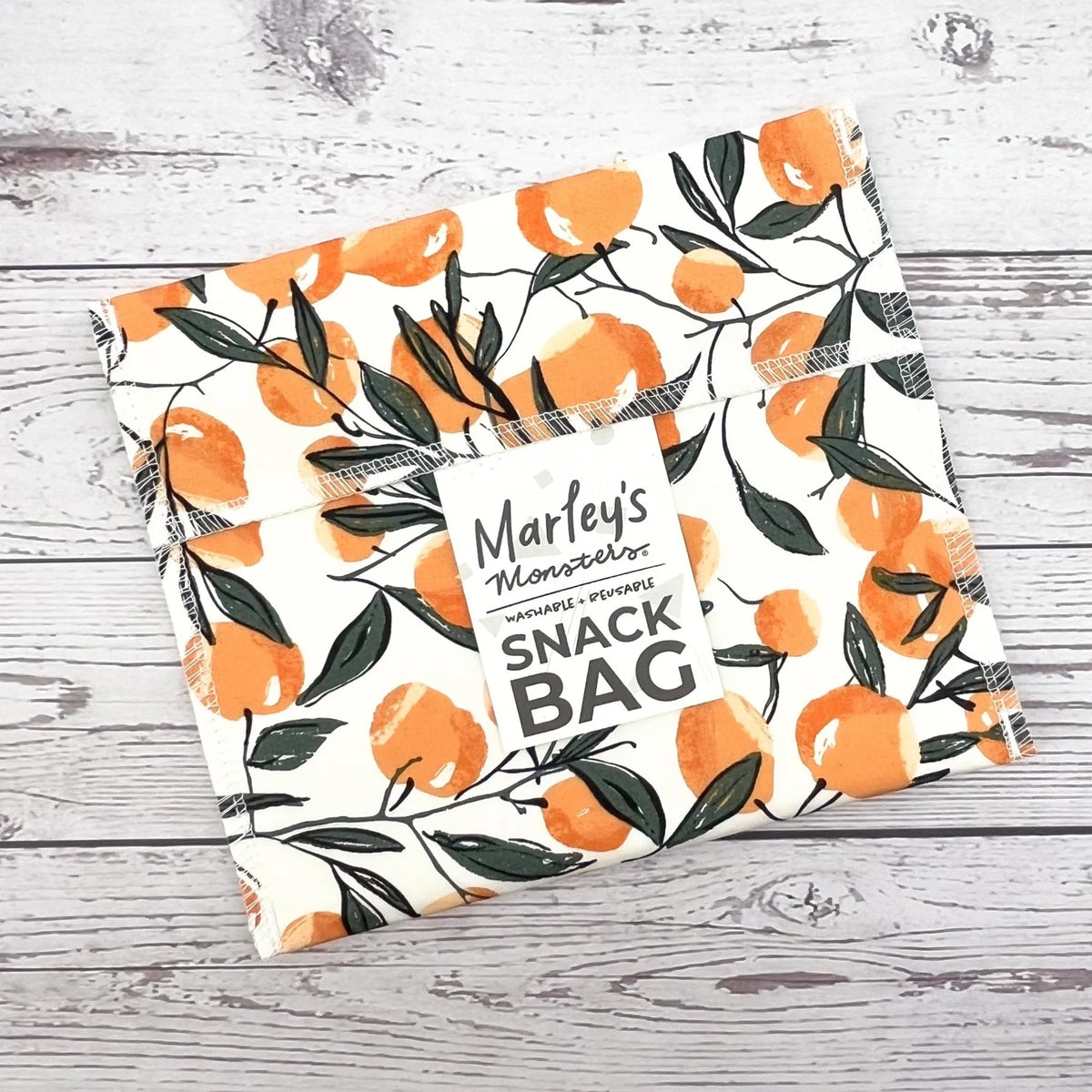 Reusable snack bag with orange floral leaf pattern and top seam detail