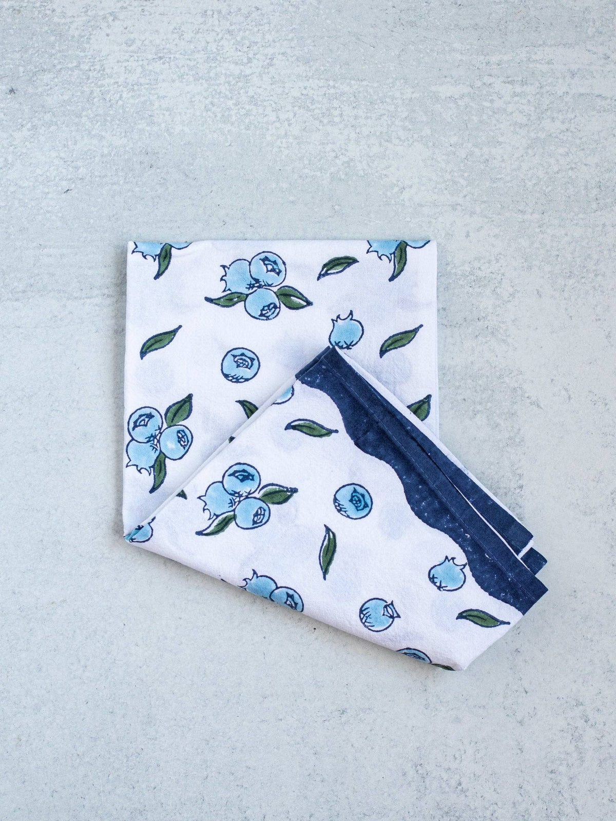 Blueberry tea towel with blue berry print and navy border, folded