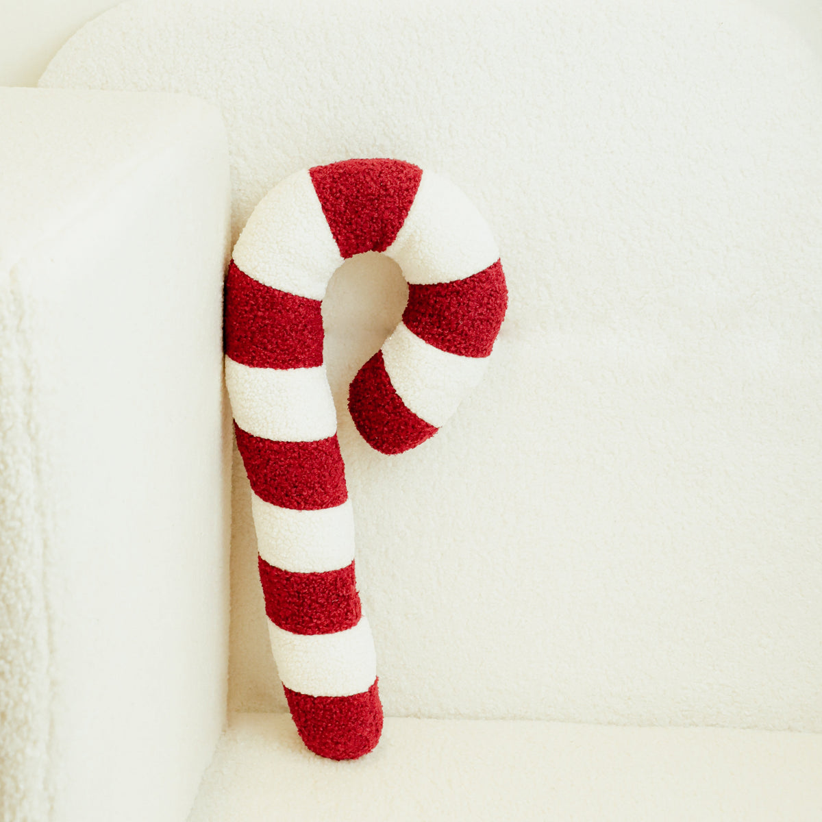 Red-and-white striped candy cane plush pillow resting on a sofa