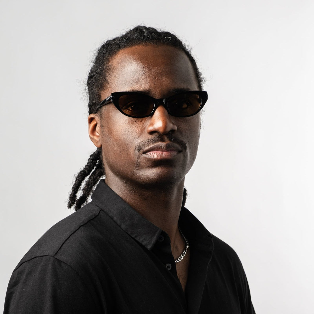 Person wearing black polarized sunglasses with bronze lenses, side portrait in black shirt.