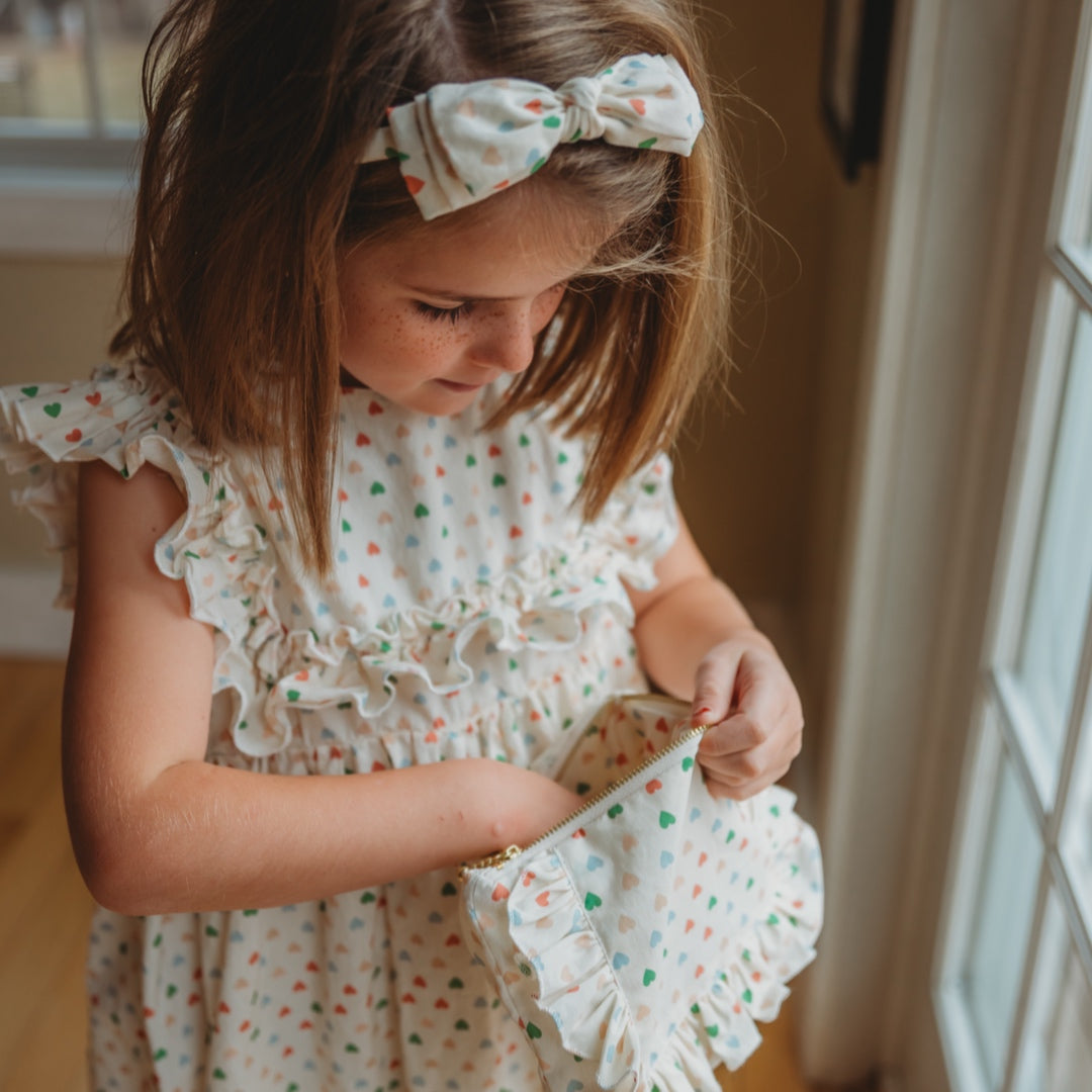 Heart-print ruffle zipper pouch held by a child, small front pouch with zipper