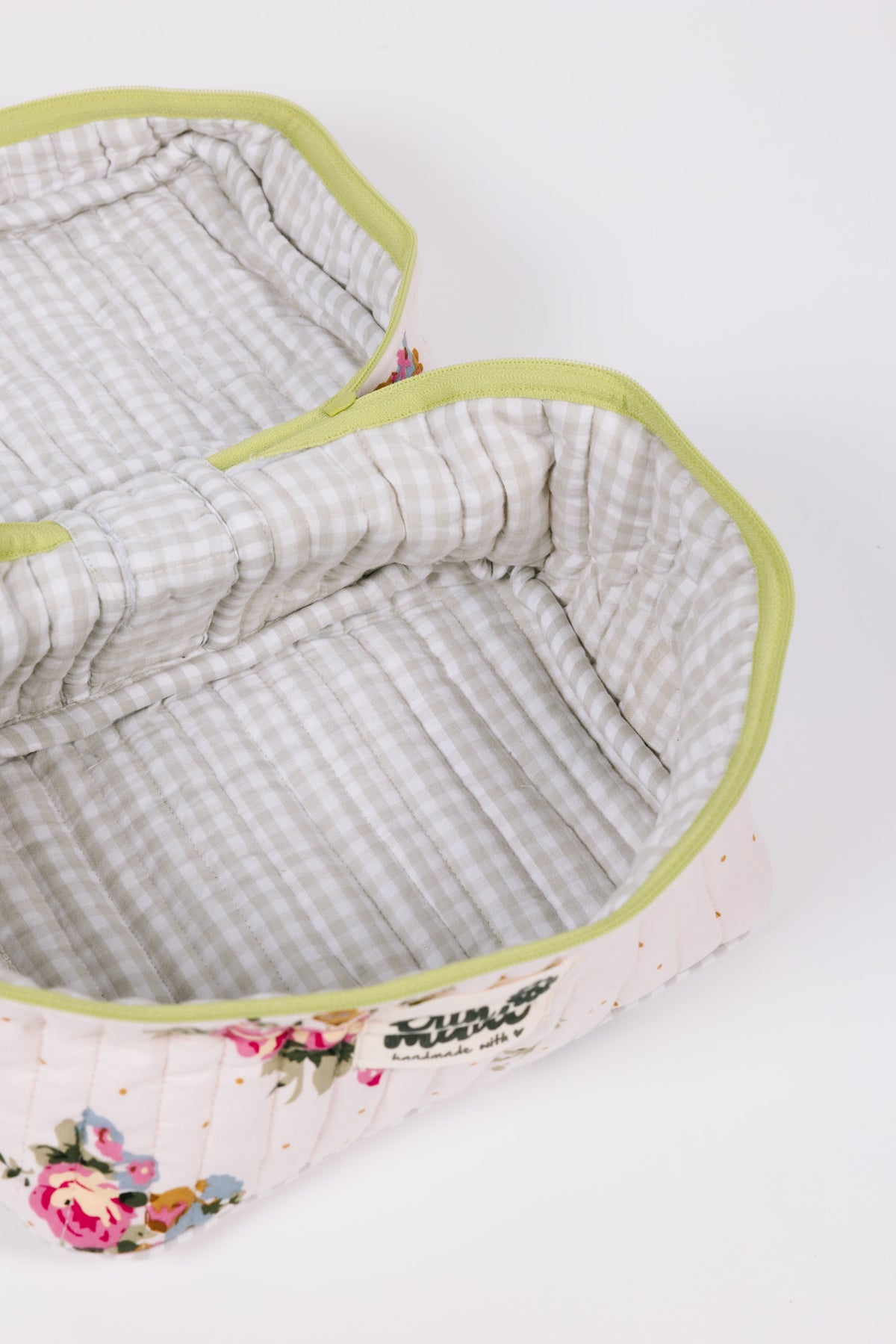 Interior view of floral quilted travel case with gray plaid lining and lime zipper trim
