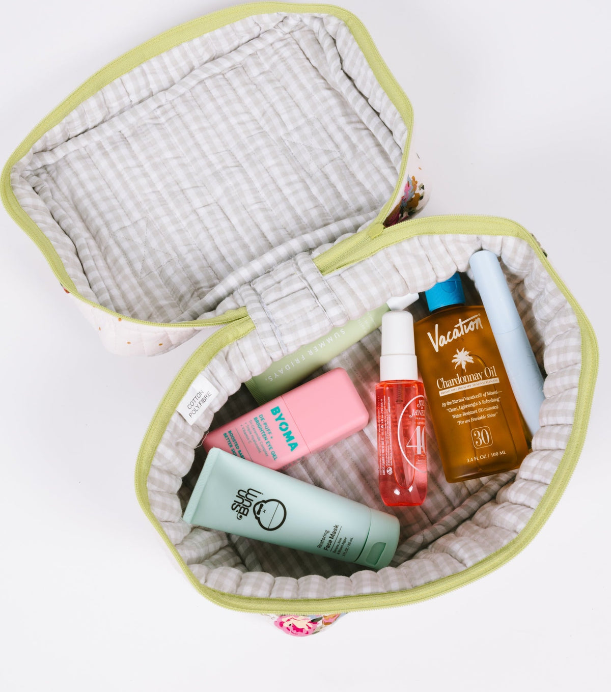 Open floral travel case with quilted lining and lime zipper, holding travel-size bottles