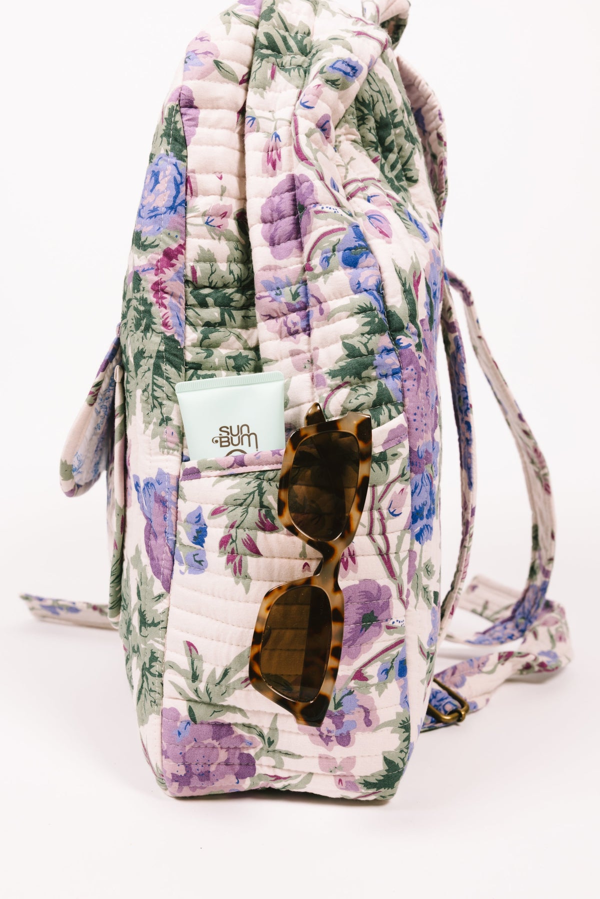 Quilted floral backpack with front pocket opening and tassel trim, cream and blue