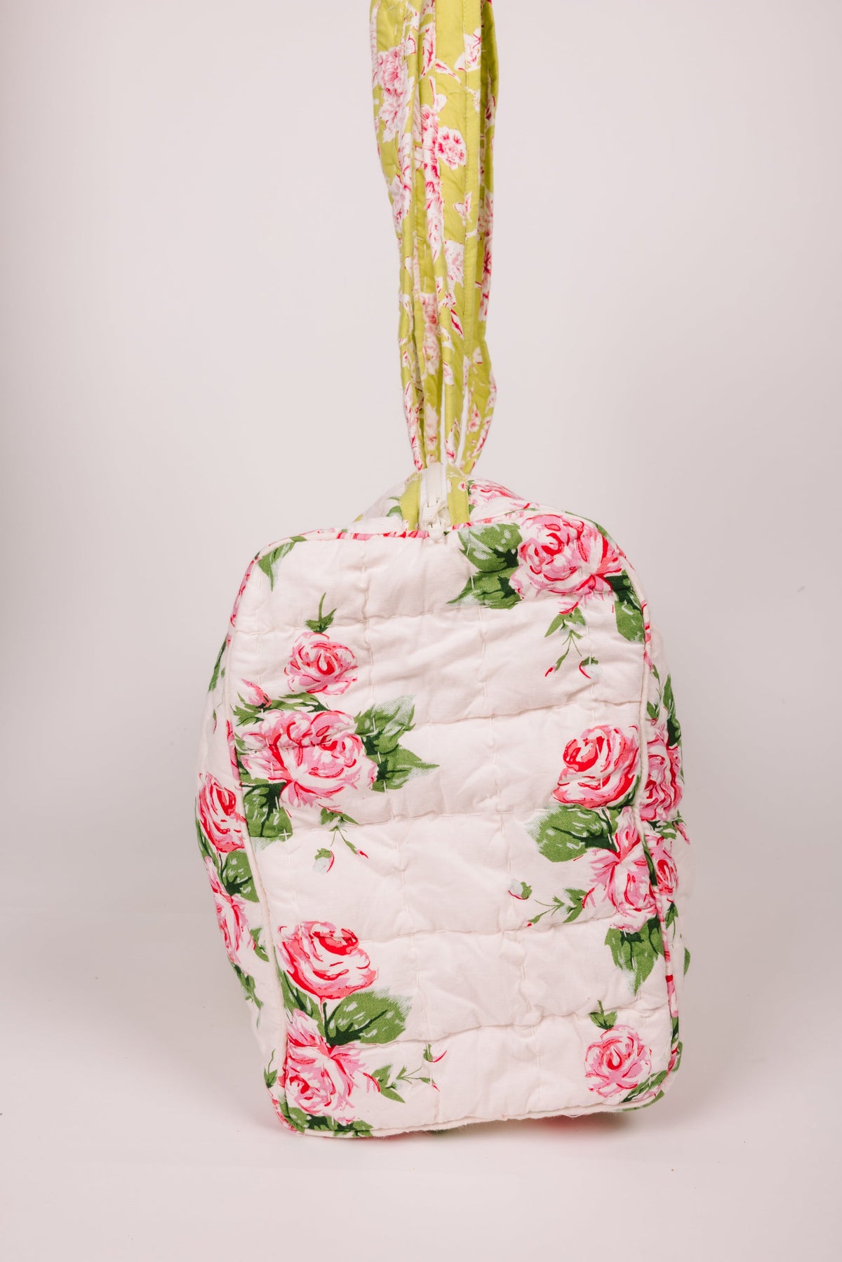 Quilted duffle bag back view with pink rose print and long yellow-green carry handle