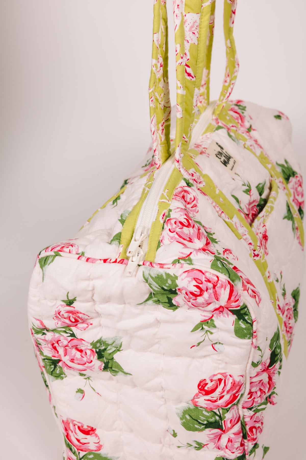 Quilted duffle bag front view with pink rose pattern and yellow-green trim