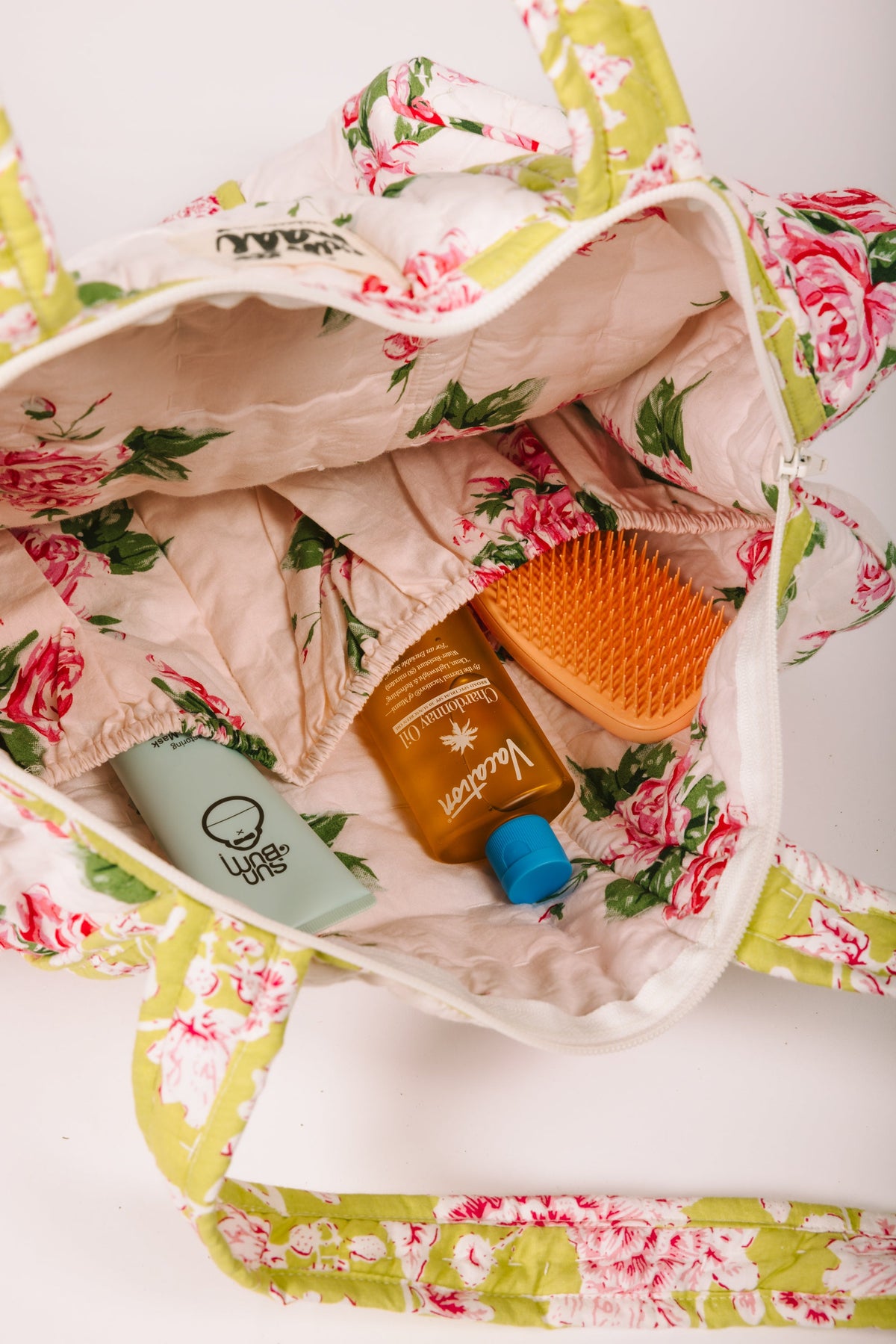 Open quilted duffle bag showing floral lining and several items inside