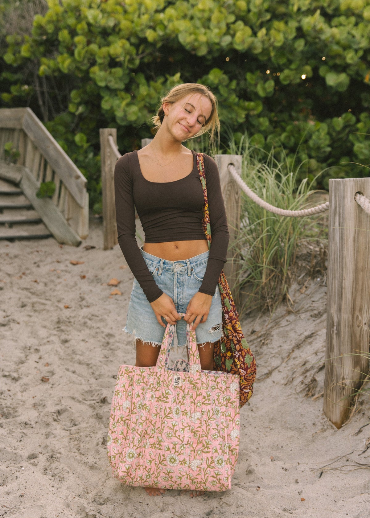 Pink floral tote bag with top handles, carried by a person