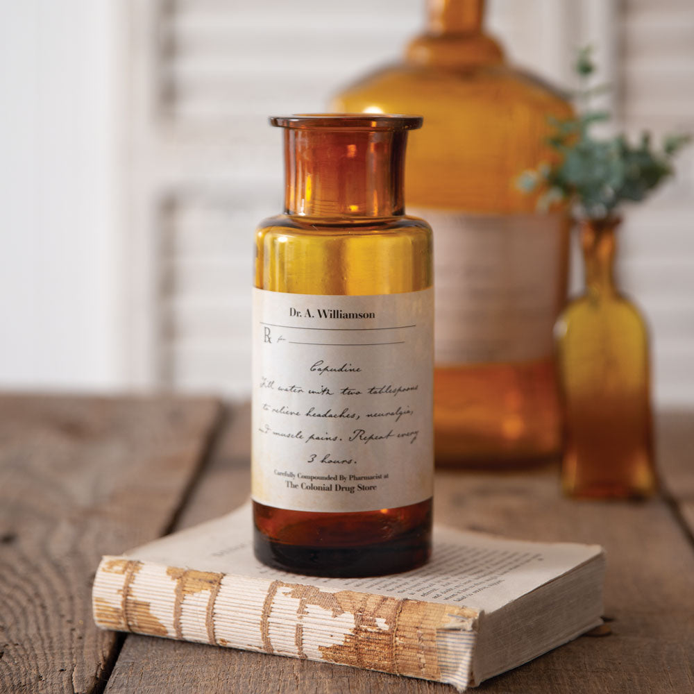 Amber apothecary bottle with bronze cap and handwritten antique label, on a book.