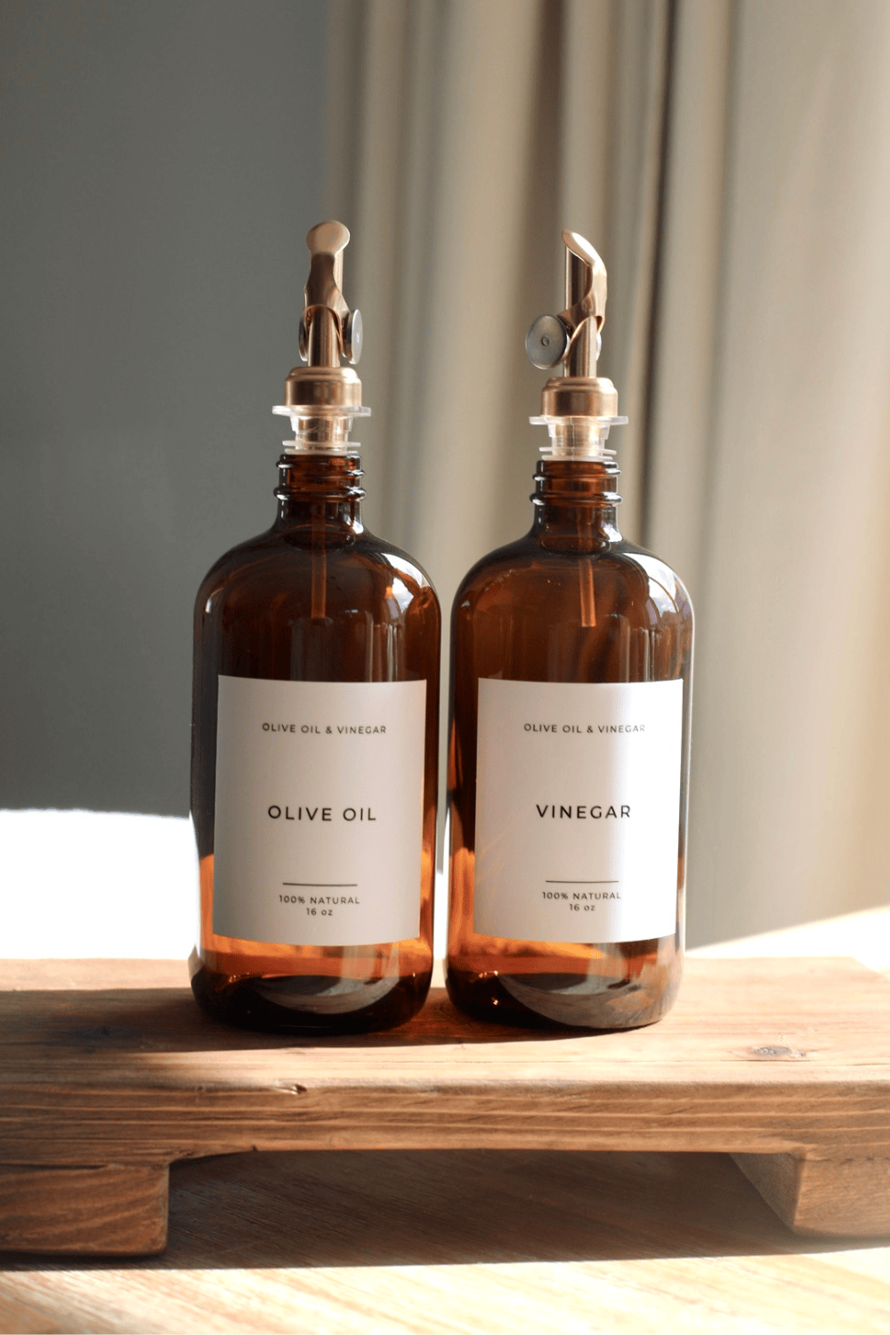Amber glass olive oil and vinegar dispenser bottles with metal pumps and white labels