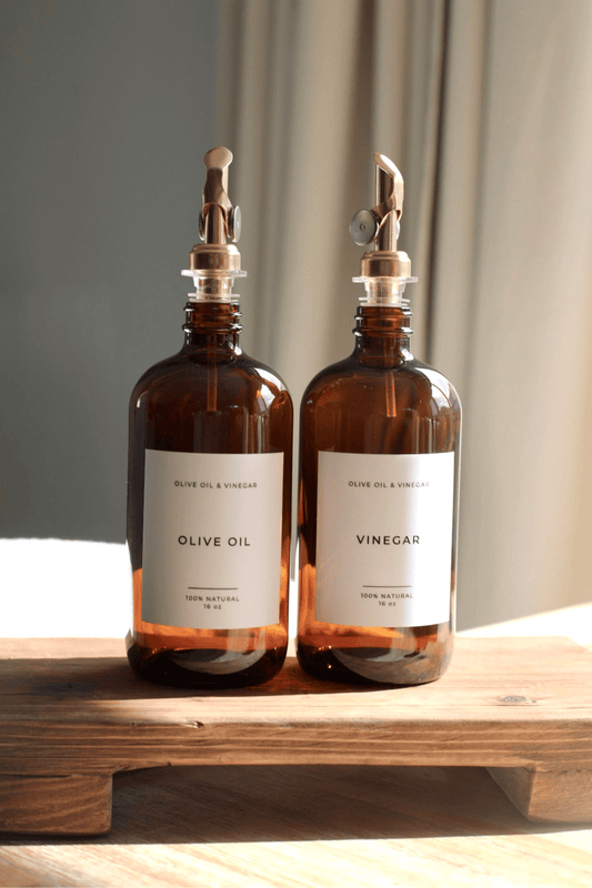 Amber glass olive oil and vinegar dispenser bottles with metal pumps and white labels
