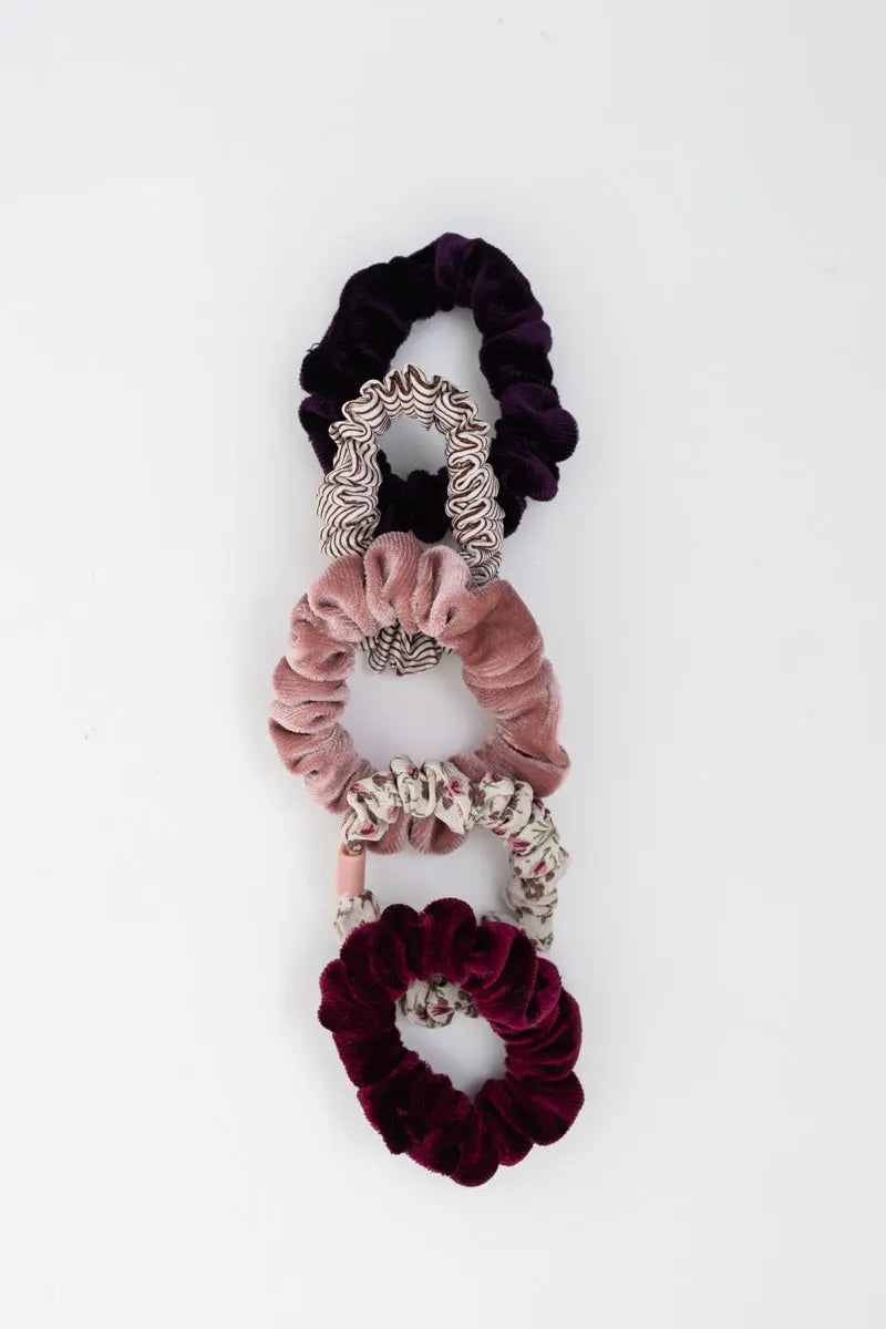 Three hair scrunchies: dark purple with white swirls, pale pink, and burgundy