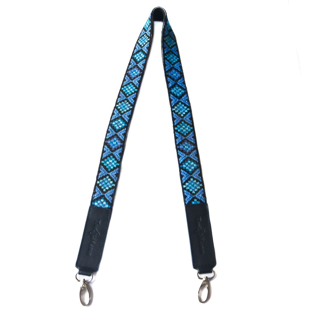Woven bag strap with blue geometric pattern and black leather backing, with metal hooks