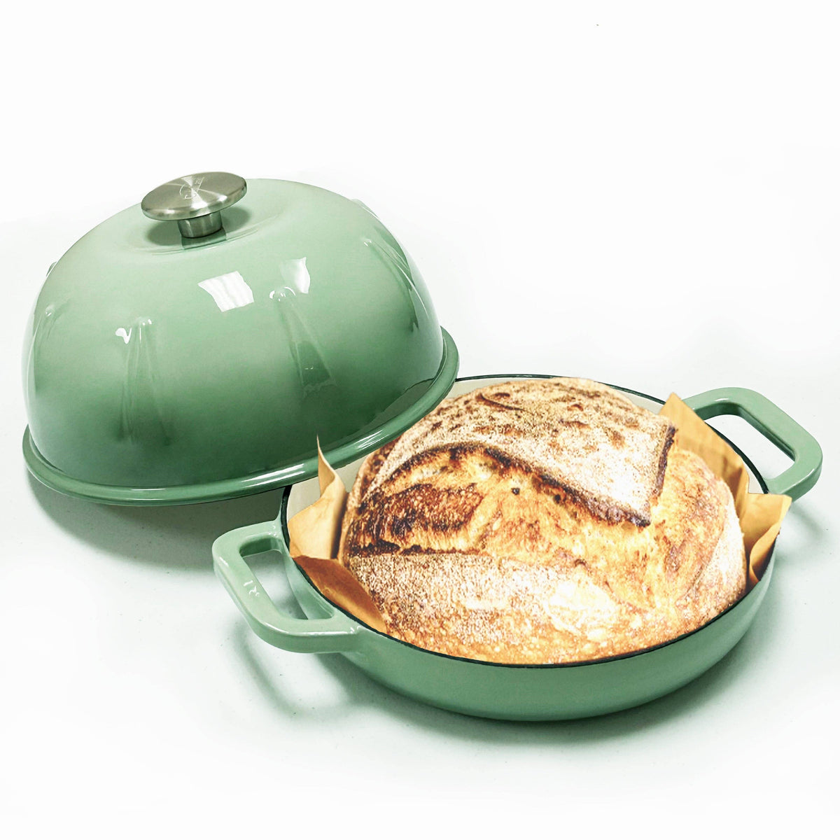 Green cast iron bread cloche with dome lid over baked loaf in base
