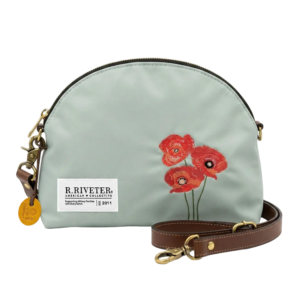 Light blue nylon bag with gold zipper, red embroidered poppies, logo patch and brown crossbody strap