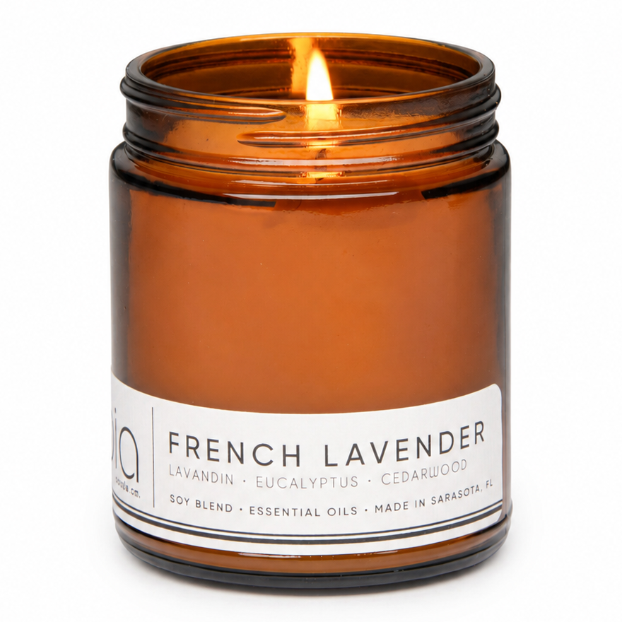 Amber soy candle jar with lit wick and French Lavender label, close-up front view