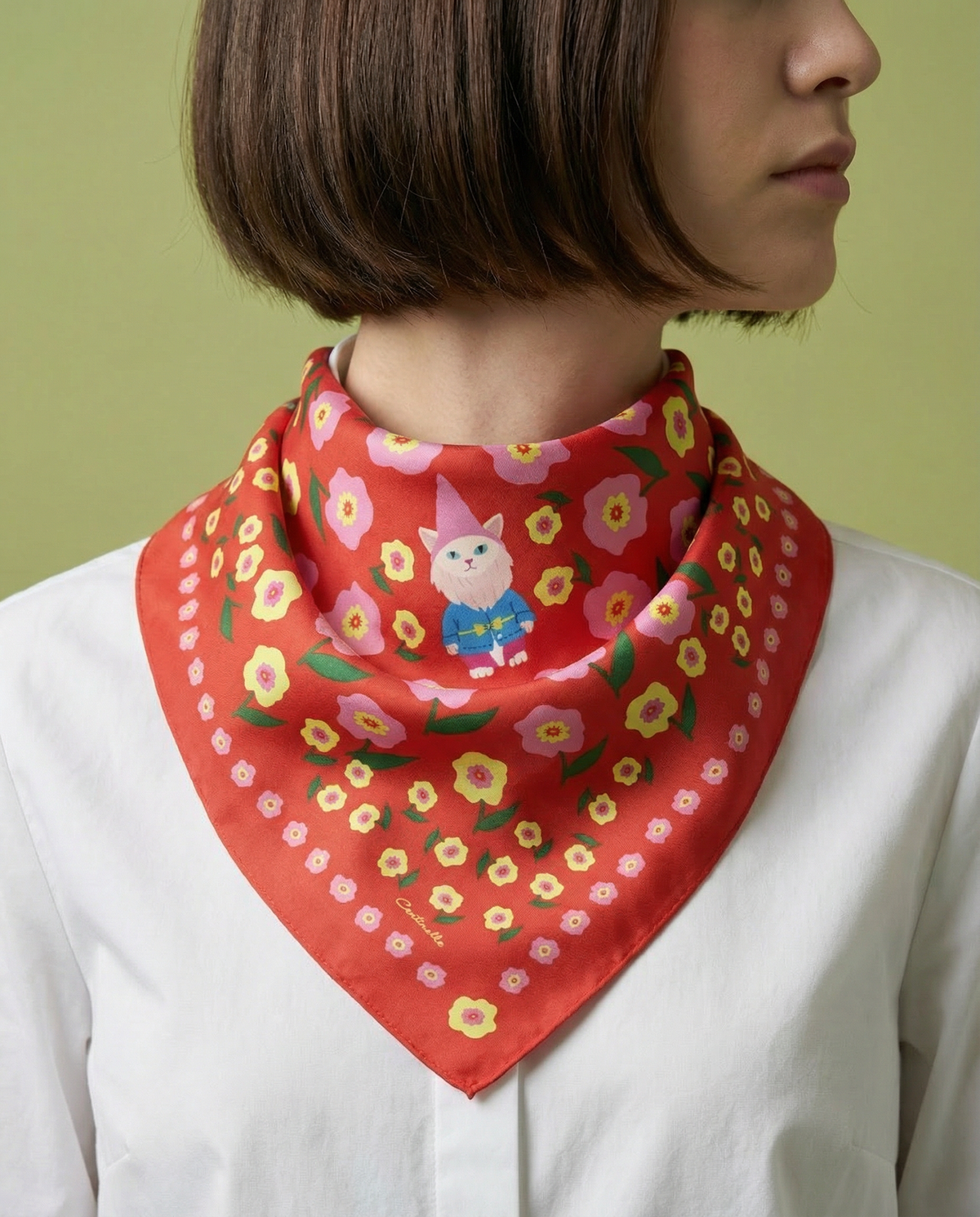 Red bandana worn at neck, with floral border and small gnome-cat graphic