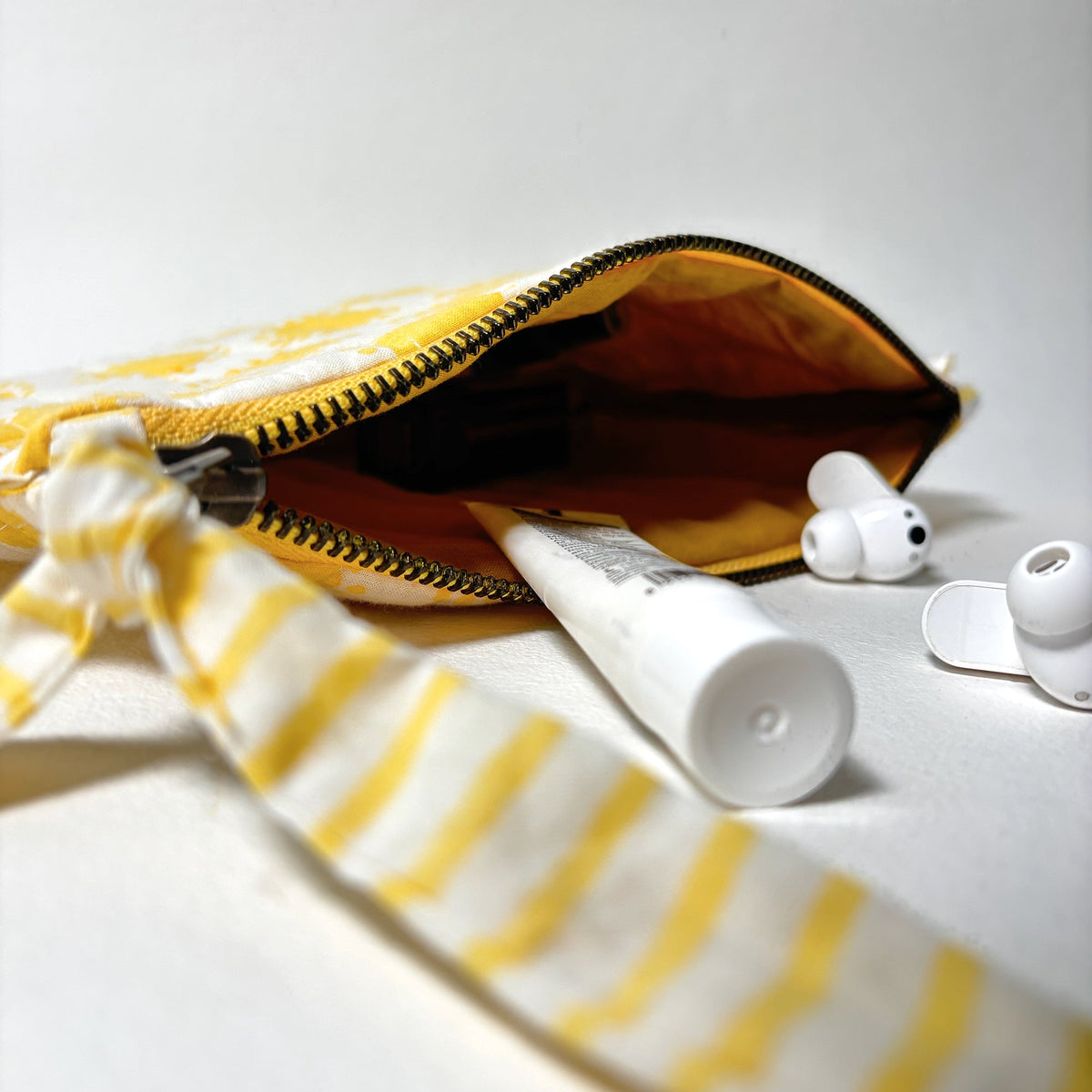 Open quilted cotton pouch with yellow sun exterior, zipper, and brown fabric lining