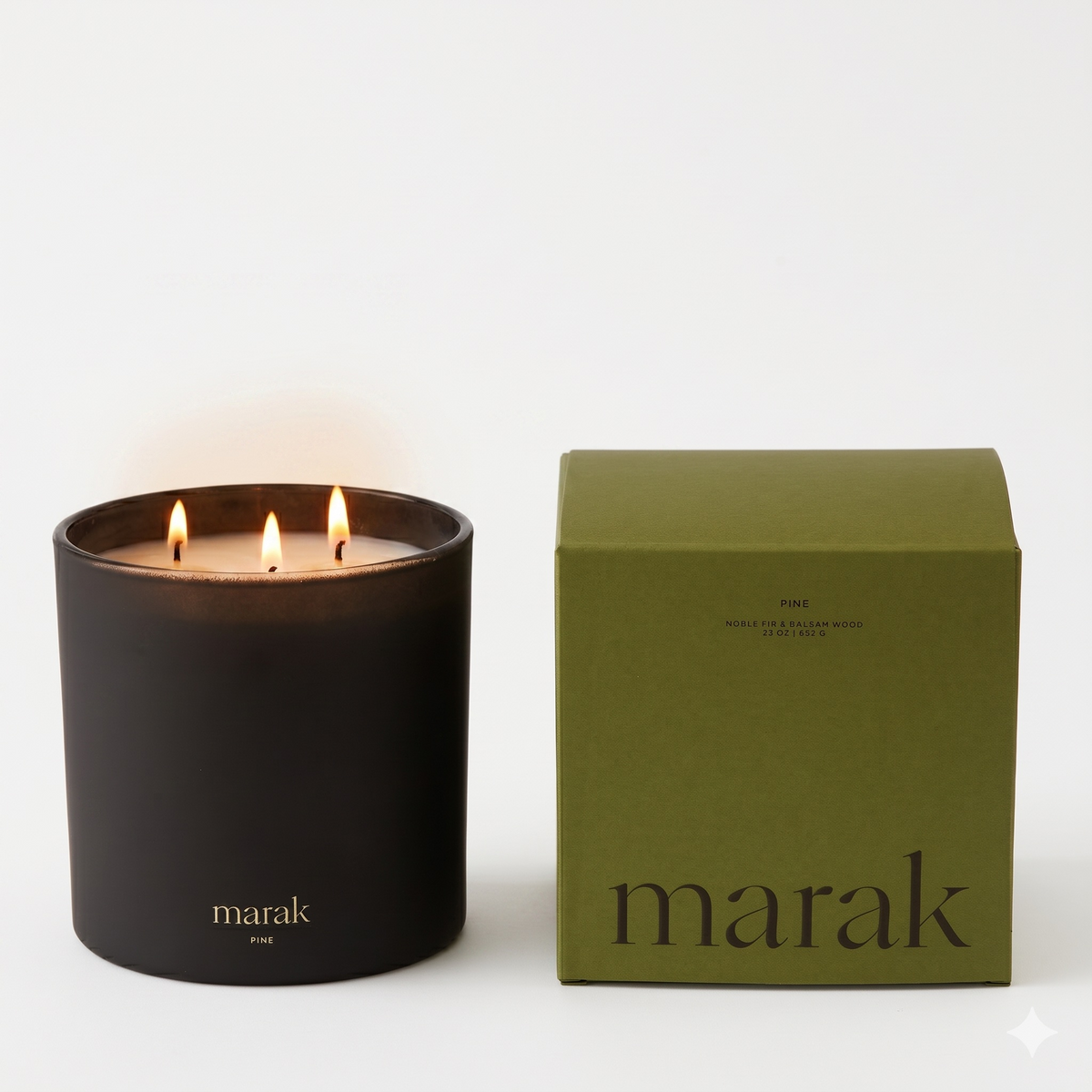 Black marak candle jar with two flames beside green marak gift box