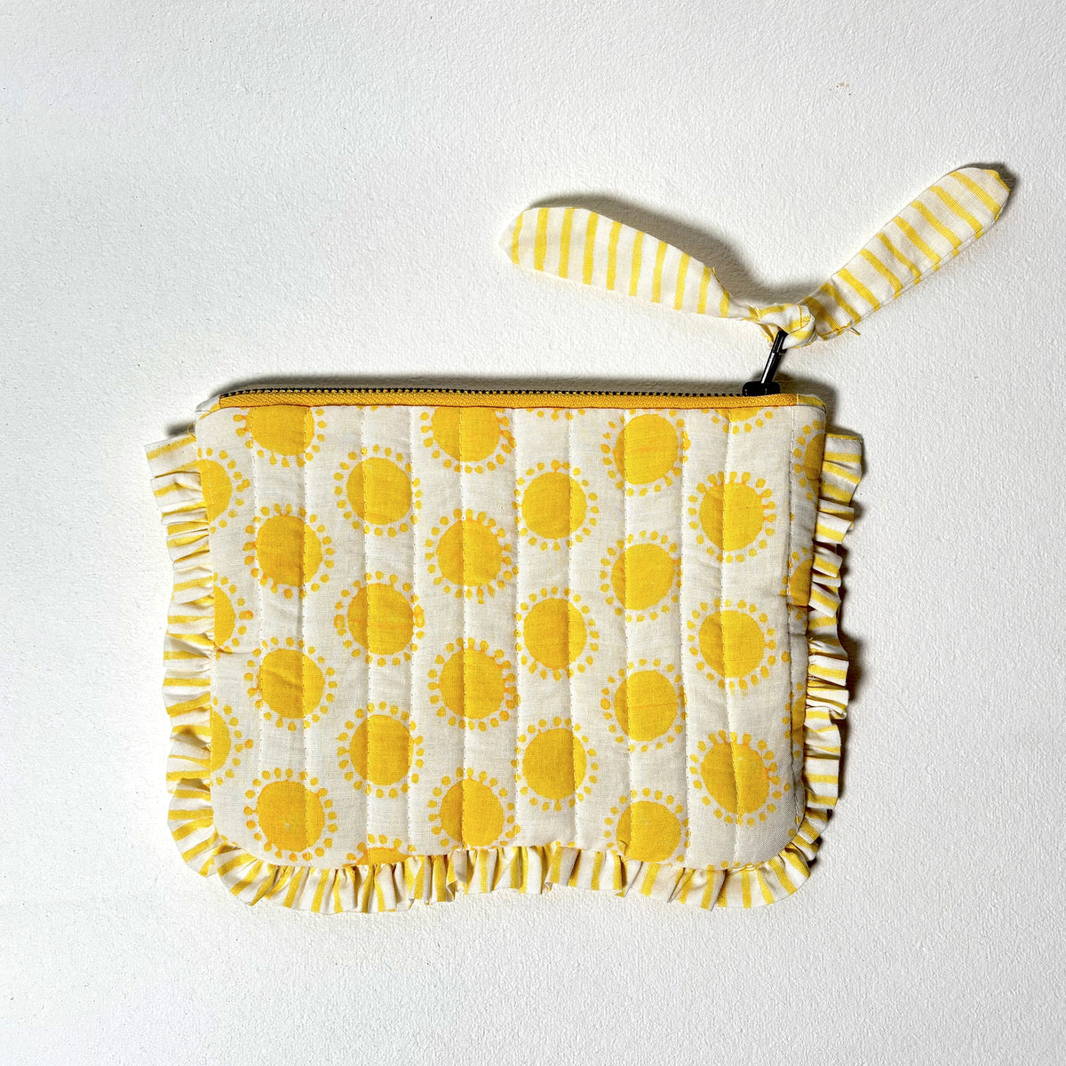 Quilted cotton travel pouch with yellow sun print, ruffle trim, and striped handle loop
