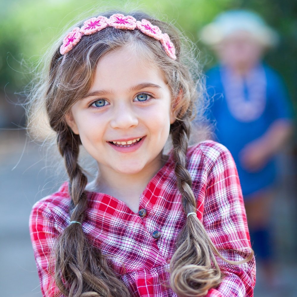 Girl wearing a pale pink knit flower crown headband with red centers
