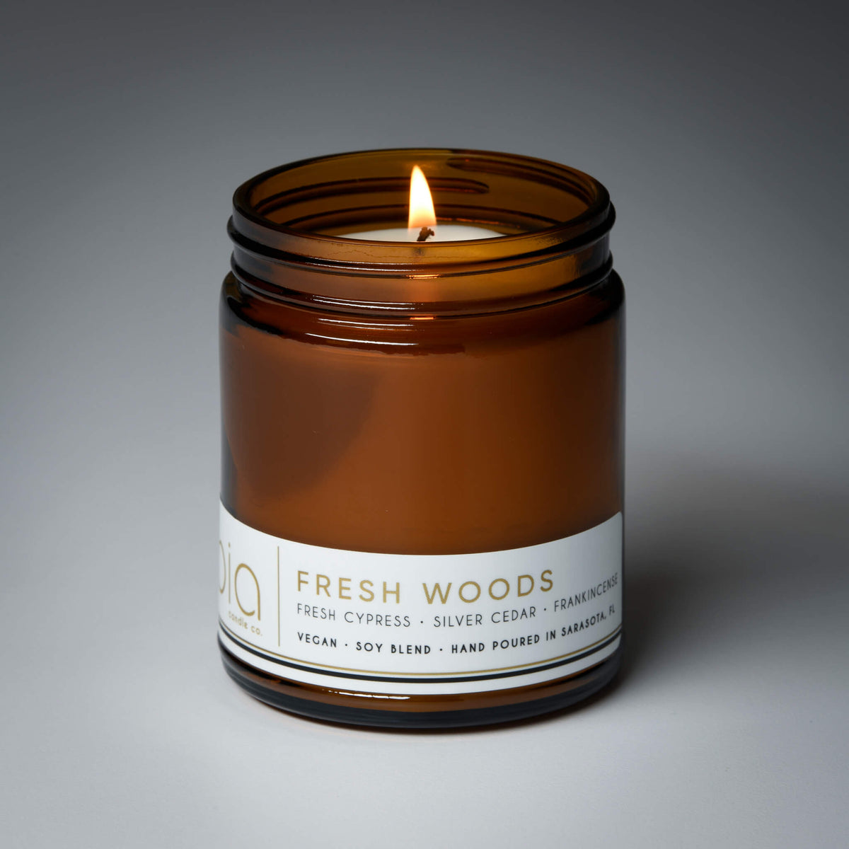 Amber glass candle jar with a centered flame and a white label around the base.