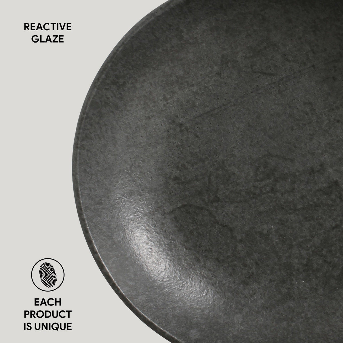 Dark gray reactive glazed pasta plate close-up, speckled texture and glossy spot