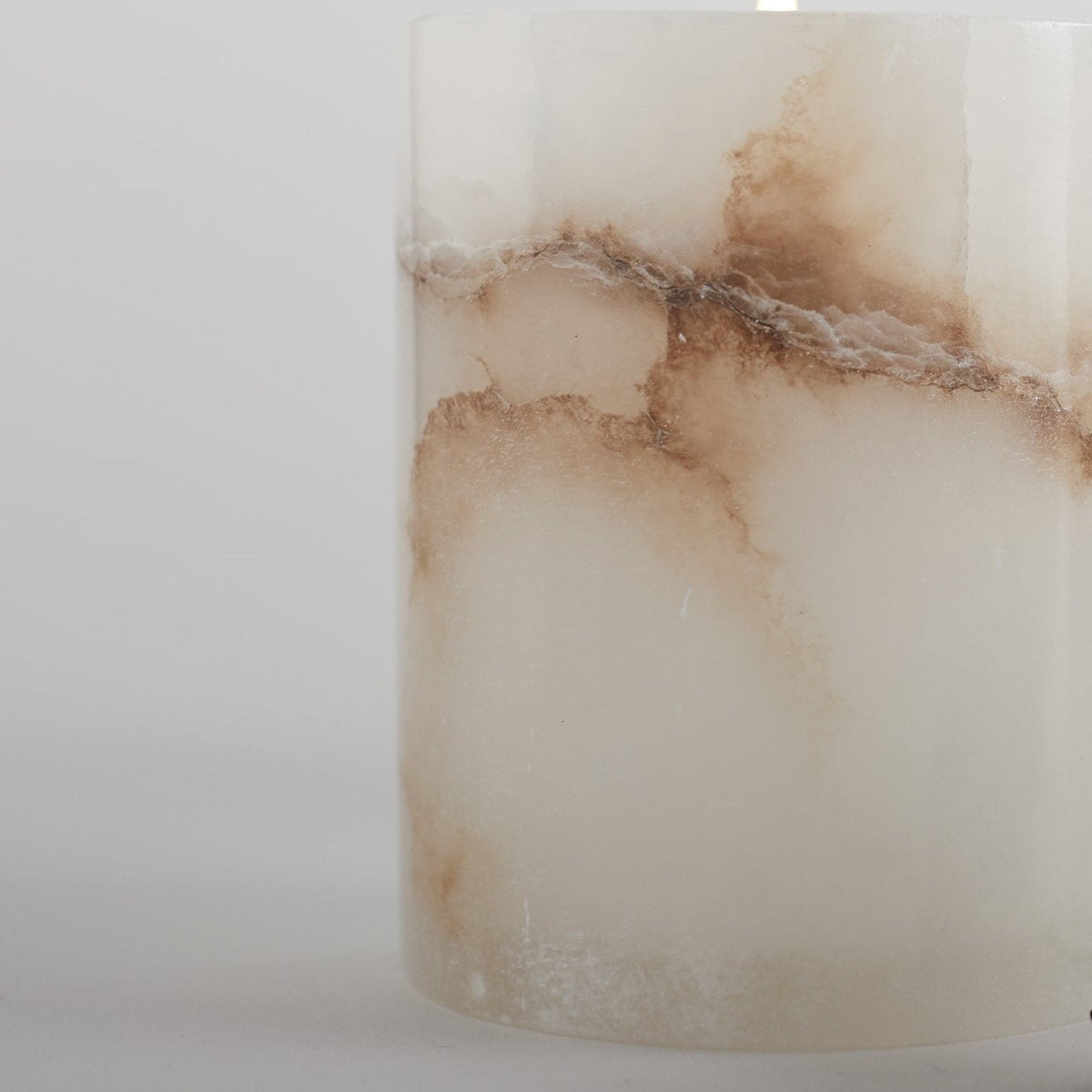 Close-up of alabaster-style votive candle texture, white cylinder with tan veining