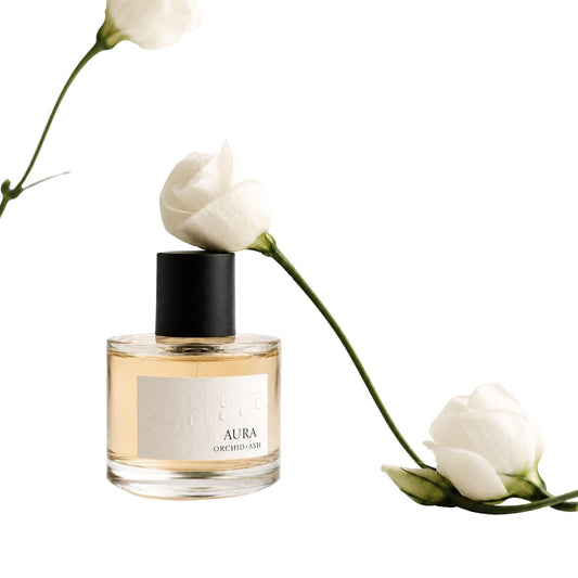 Clear glass perfume bottle with black cap, framed by white flowers